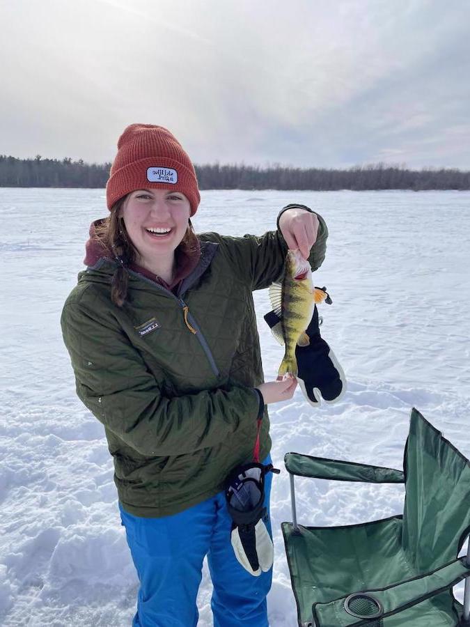 a women holding a fish up in the snow